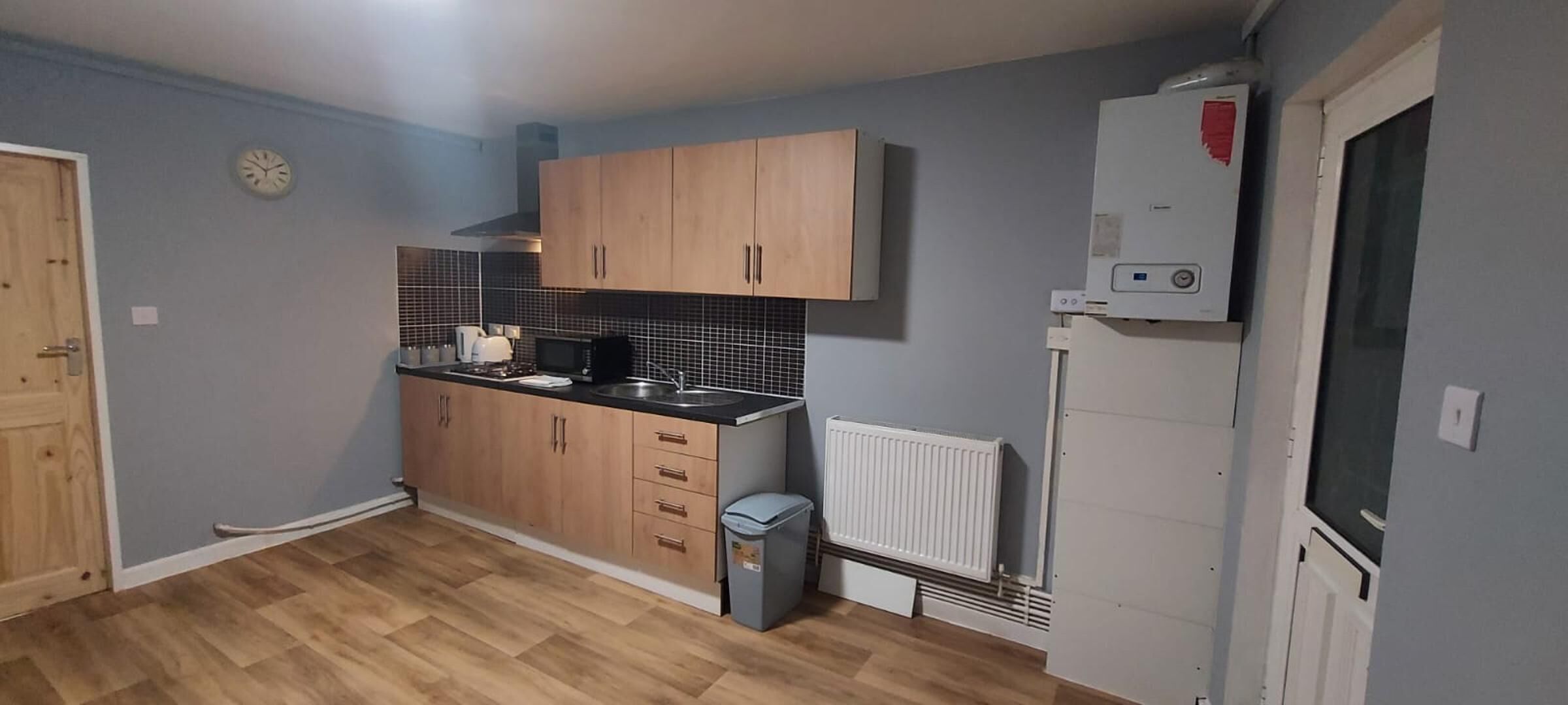 A compact kitchen with wooden cabinets, a microwave, and a white refrigerator.
