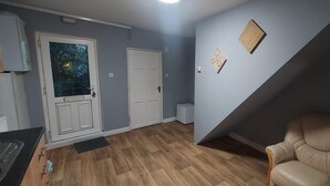 A room with a kitchen area, a dining table, and a beige leather chair. - 2 Bedrooms Apartment in Main Street Mexborough (Mexborough)
