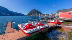Un muelle con varias embarcaciones pequeñas rojas y blancas, un embarcadero de madera y un edificio de fachada roja.