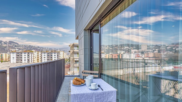 A balcony with a table set for breakfast, overlooking a cityscape. - Icon H 405 Suite Business (Lugano)