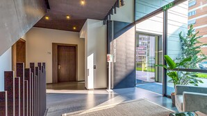 A modern hotel lobby with a reception desk, a staircase, and a large window offering a view of the outside. - Icon H 505 Suite Business (Lugano)