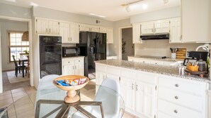 A modern kitchen with white cabinetry, a granite countertop, and stainless steel appliances.