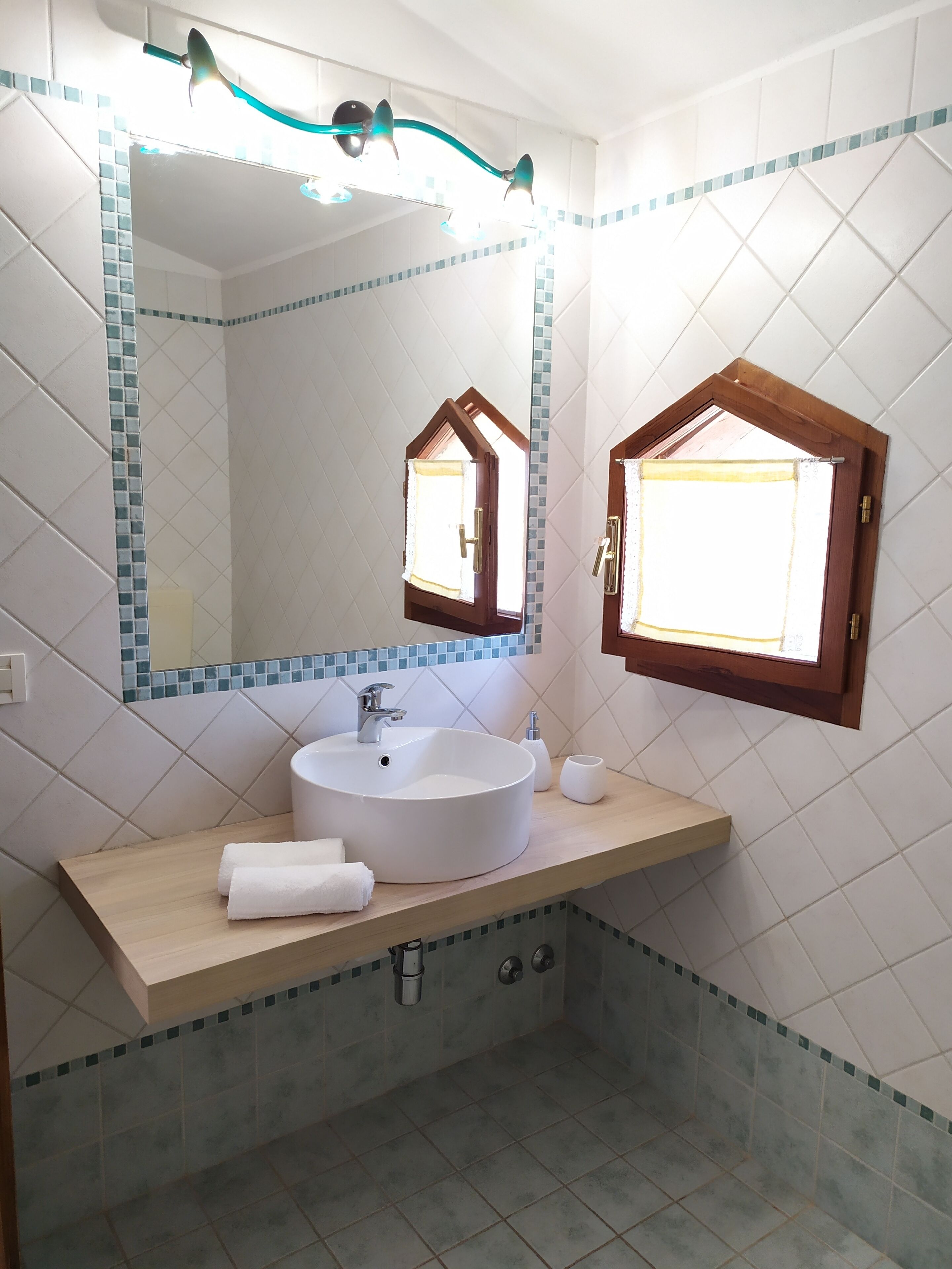 Une salle de bain avec un lavabo rond, un miroir avec un cadre en bois et une fenêtre avec un cadre en bois.