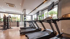 Un gimnasio con cintas de correr, equipo de ejercicio y ventanas amplias que ofrecen vistas al exterior.