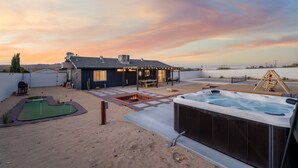 A backyard with a hot tub, a patio, and a small putting green. - Vista del Valle 🌵 Pickleball + Pitch&Putt + Hot Tub + Pool (Joshua Tree)