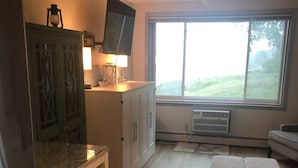 Una cocina con una mesa de comedor, un televisor montado en la pared y un amplio ventanal con vistas al exterior.
