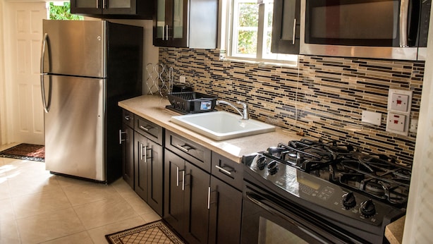 Una cocina moderna con electrodomésticos de acero inoxidable, un salpicadero de azulejos y un ventanal que aporta luz natural.