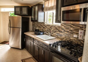 Cozinha moderna com eletrodomésticos de aço inoxidável, painel de azulejos e janela que oferece iluminação natural.