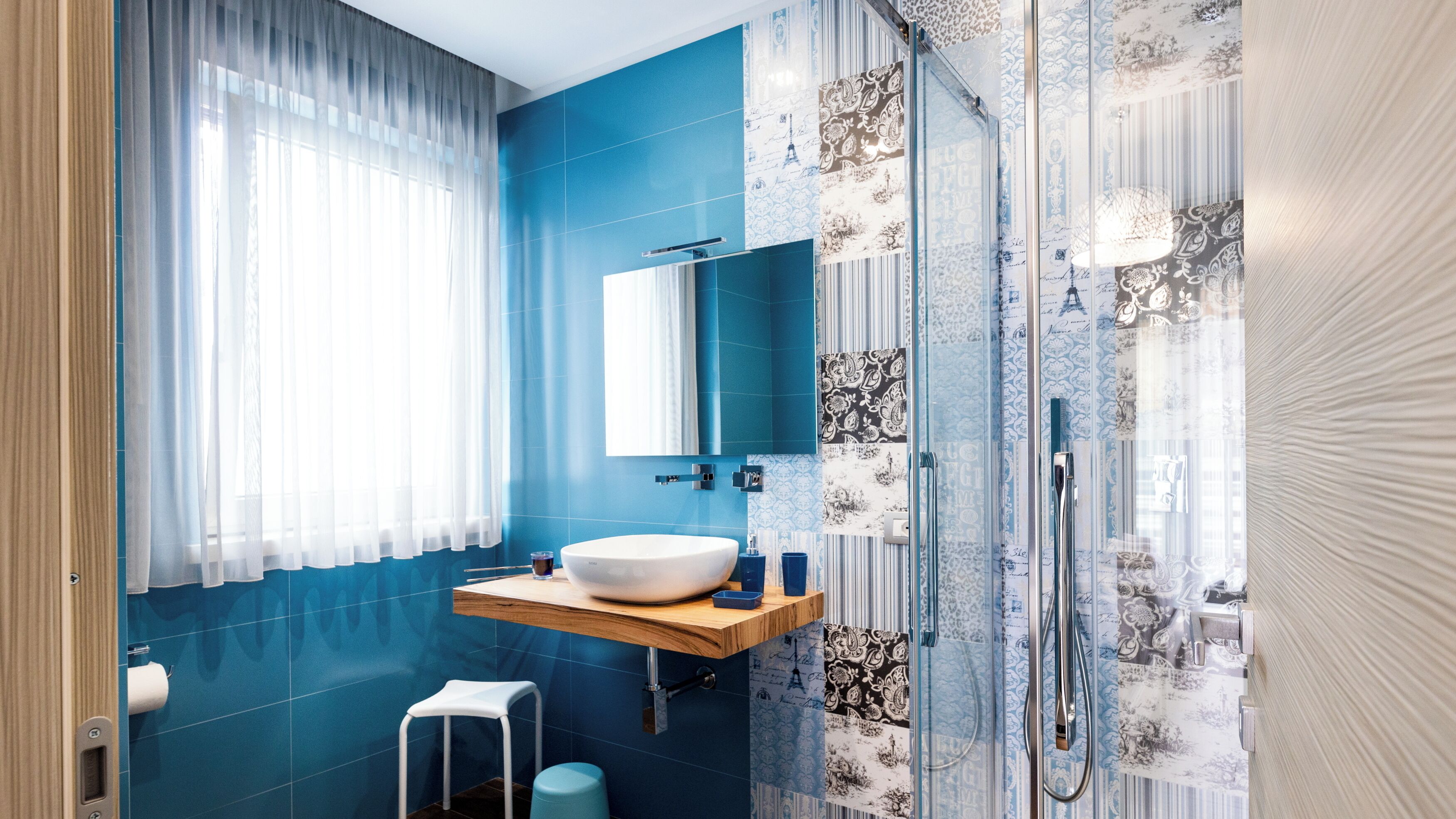 A modern bathroom with a large white sink, a mirror, and a shower area.