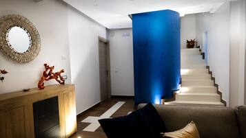 A modern interior with a wooden console, a blue accent wall, and a staircase.