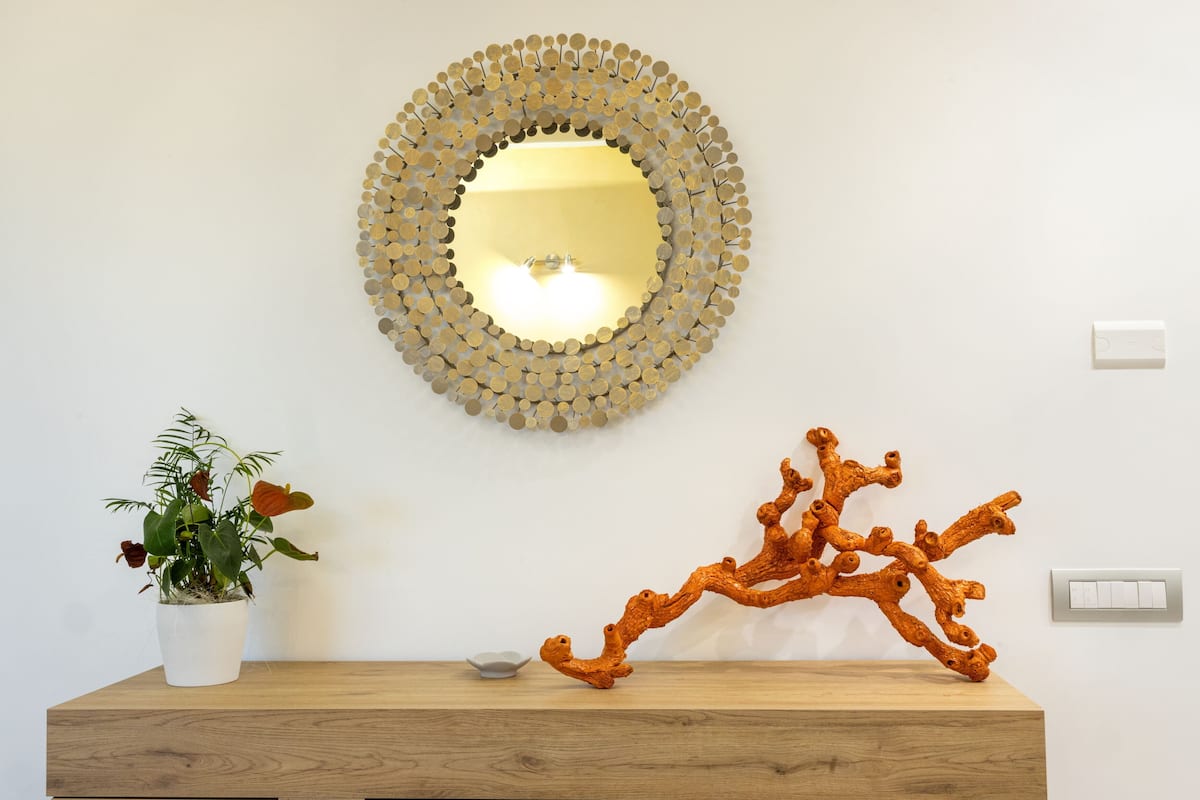 A wooden console table with a potted plant and a sculptural piece.