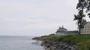 A rocky shoreline with a large building in the background.