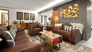 A modern living room with leather sofas, a coffee table, and decorative wall panels.