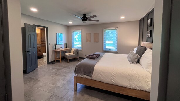 A bedroom with a bed, a desk, a chair, and a ceiling fan.