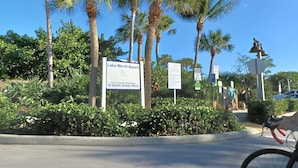 A sign for Lake Worth Beach, a parking sign, and a bicycle in the foreground.