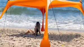 Una playa con una amplia estructura tipo toldo naranja.