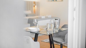 Un espace repas moderne avec une table en verre, de l’assiette blanche et des bougies.