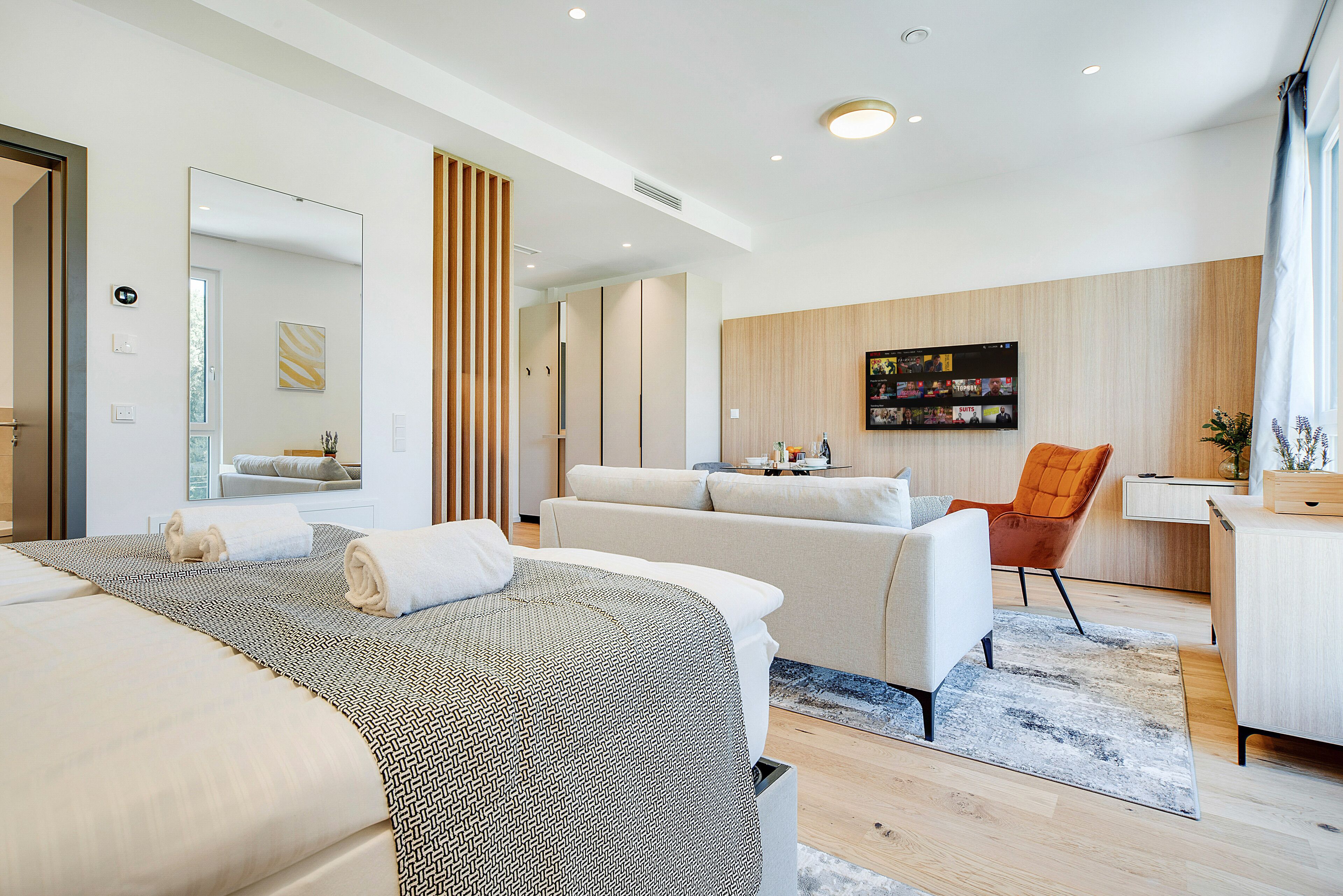 Een moderne hotelkamer met een groot bed, een bank, een bureau en een aan de muur bevestigde televisie.