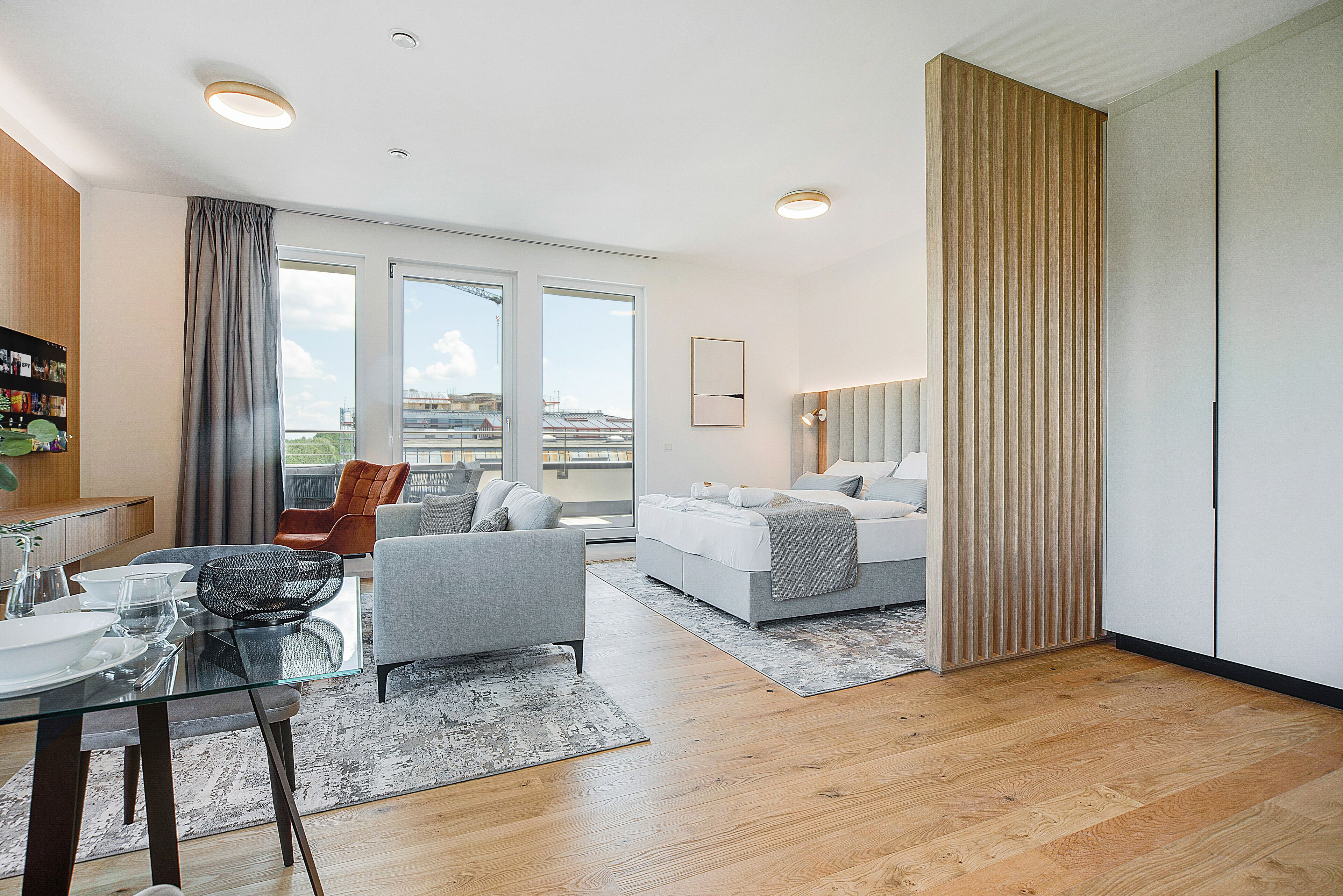Uma sala de estar moderna com uma mesa de jantar de vidro, um sofá e uma cama.