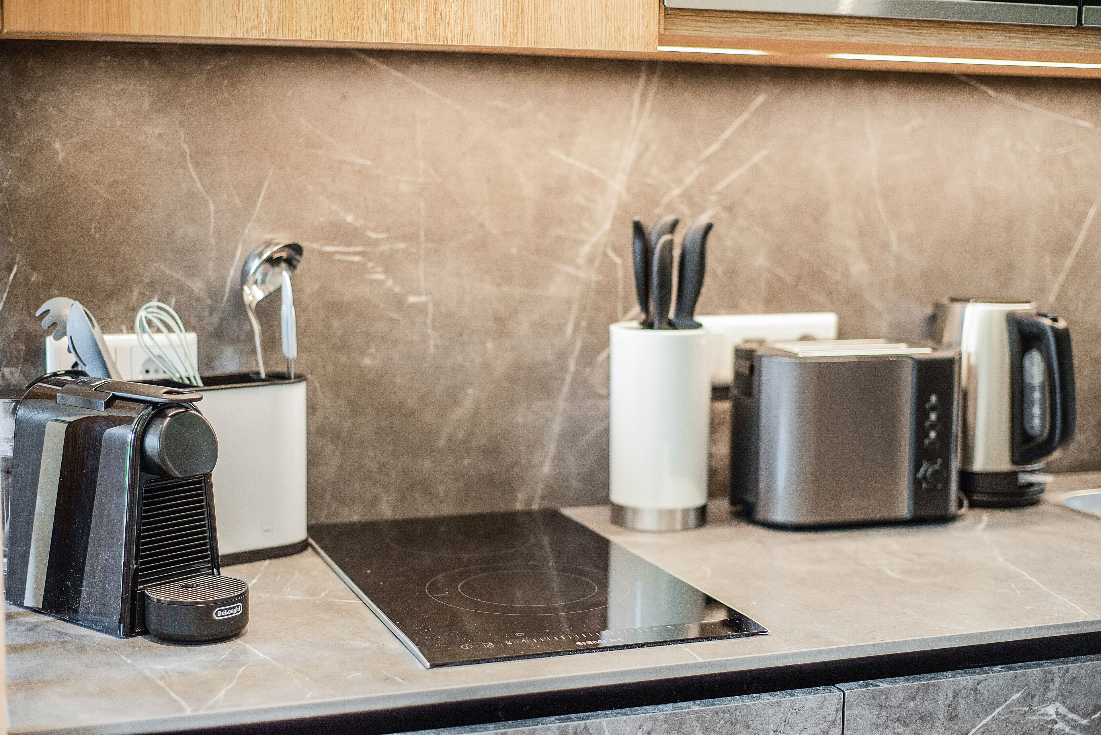 A modern kitchen with a built-in induction cooktop, a coffee maker, and a kettle.