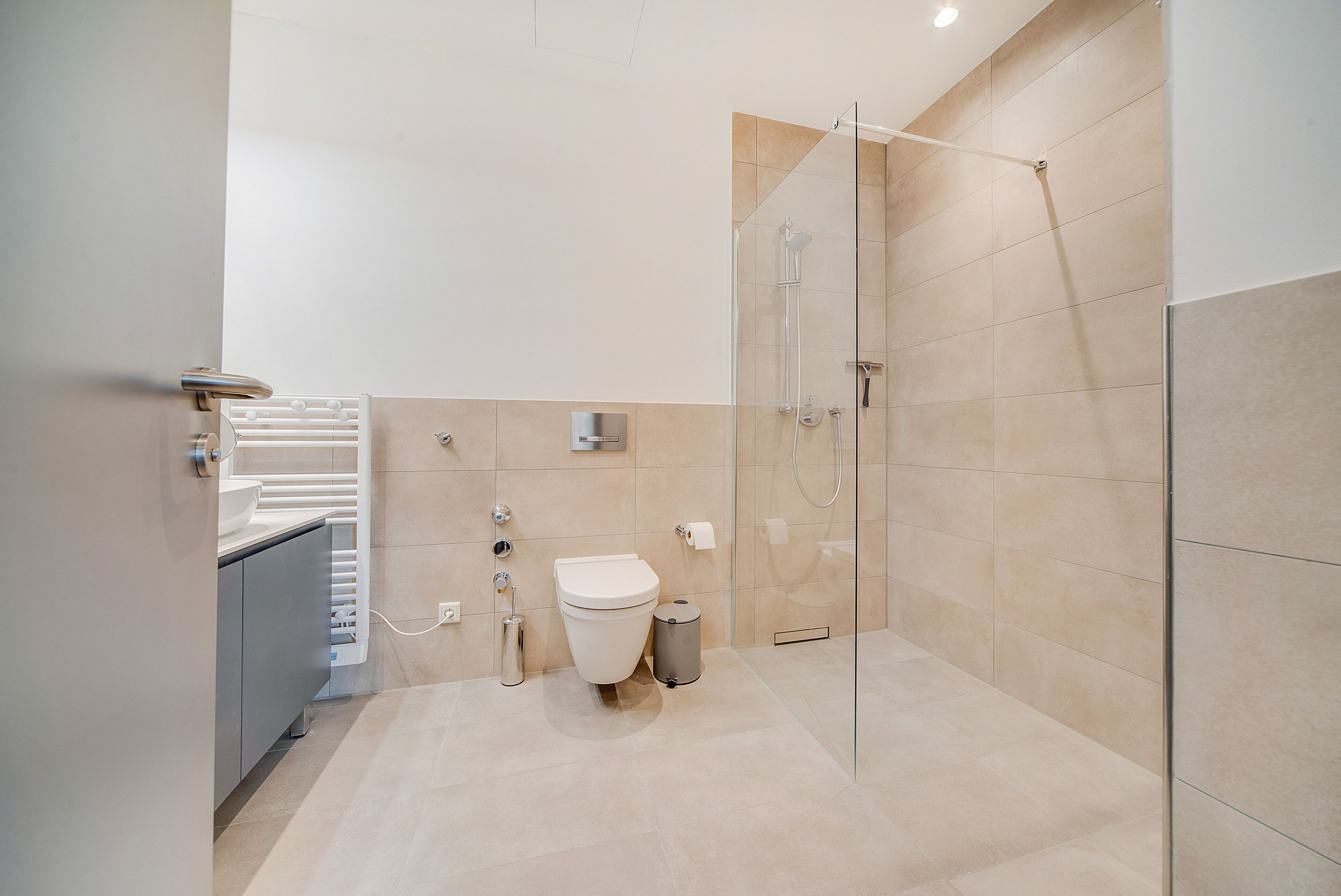 Een moderne badkamer met een douchecabine van glas, een toilet en een wastafel.