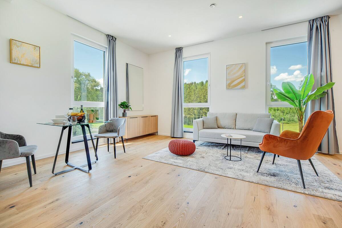 A modern living room with a sofa, chairs, a coffee table, and a dining area with a table and chairs.