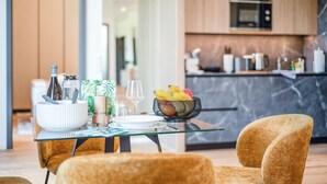 Une cuisine moderne équipée d’un four à micro-ondes, de placards et d’une table en verre, agrémentée d’un saladier de fruits, de verres à vin et d’une bouteille.