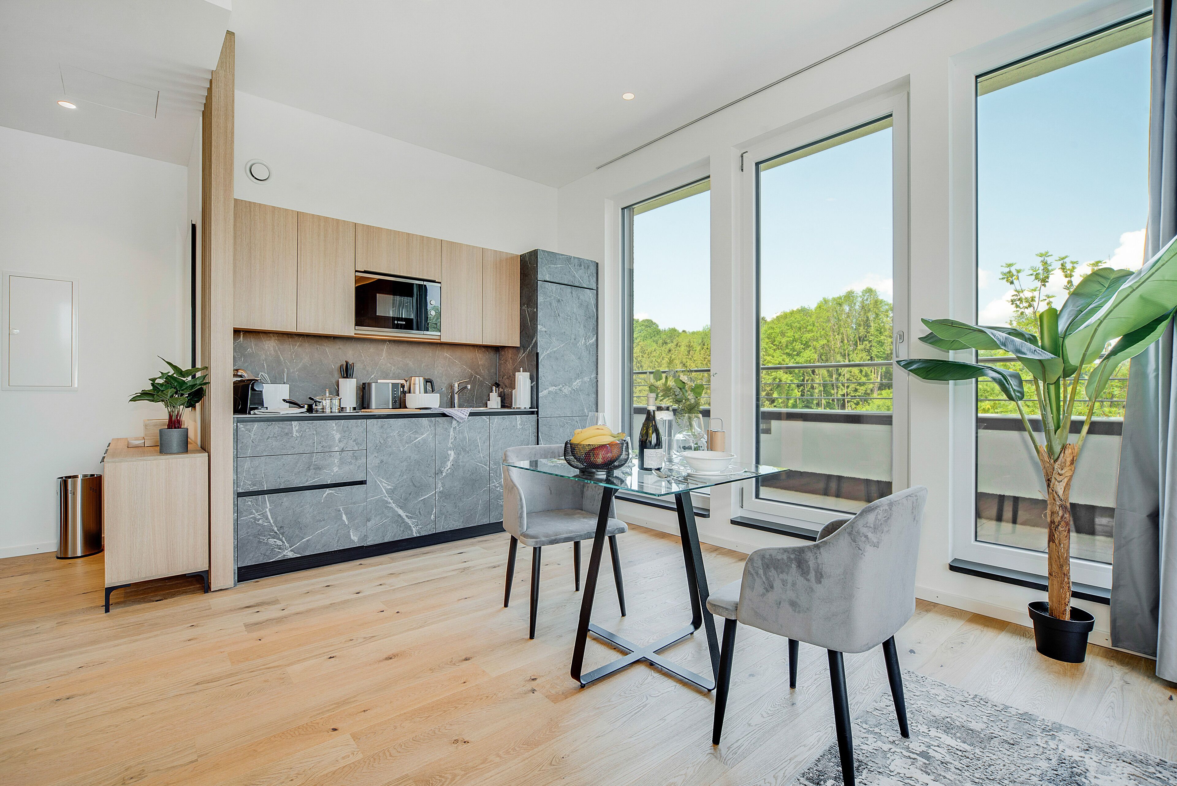Una cocina moderna con comedor, ventanas amplias y una planta en maceta.