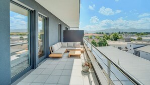 Un balcon avec un canapé, une table basse et une plante en pot.