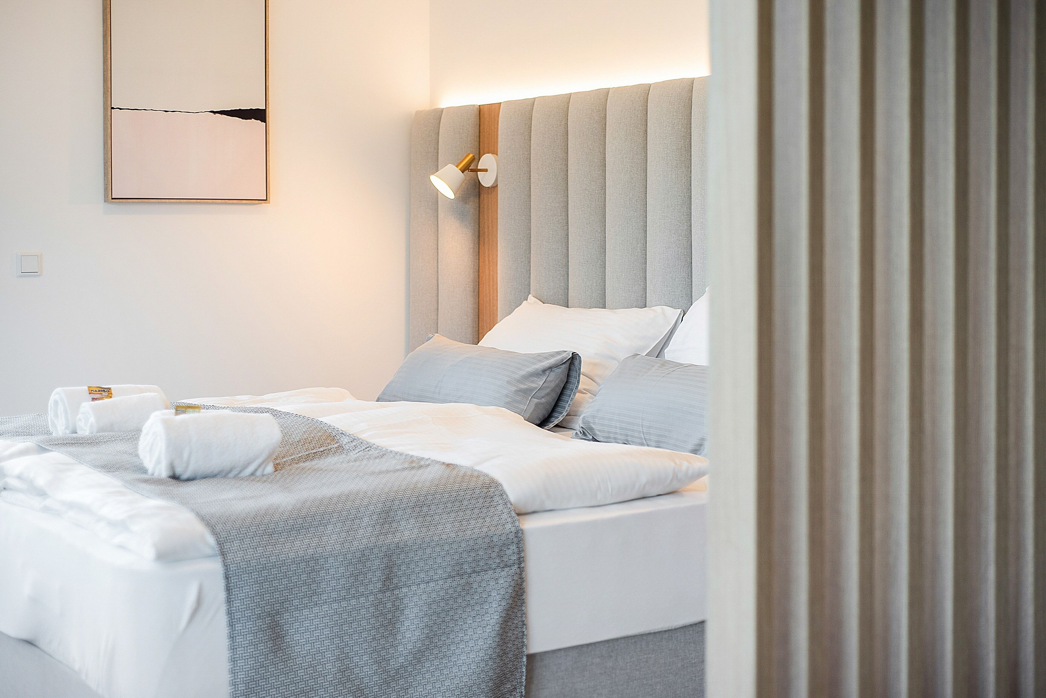 Ein Hotelzimmer mit einem großen Bett, einem Nachttisch, einer Lampe und einem an der Wand befestigten Kunstwerk.
