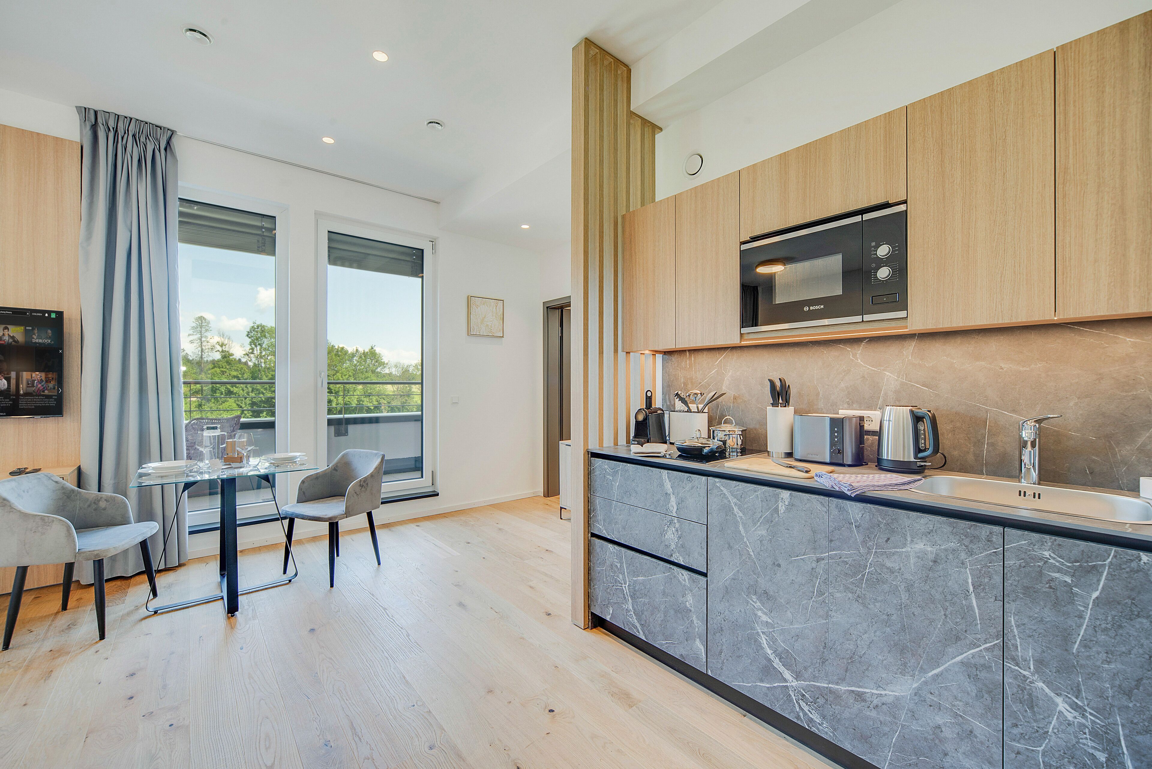Una cocina moderna con microondas integrado, una isla grande con pileta y un comedor con mesa y sillas de vidrio.