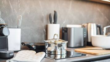A modern kitchen with a coffee maker, a kettle, a toaster, and a cutting board on the counter.