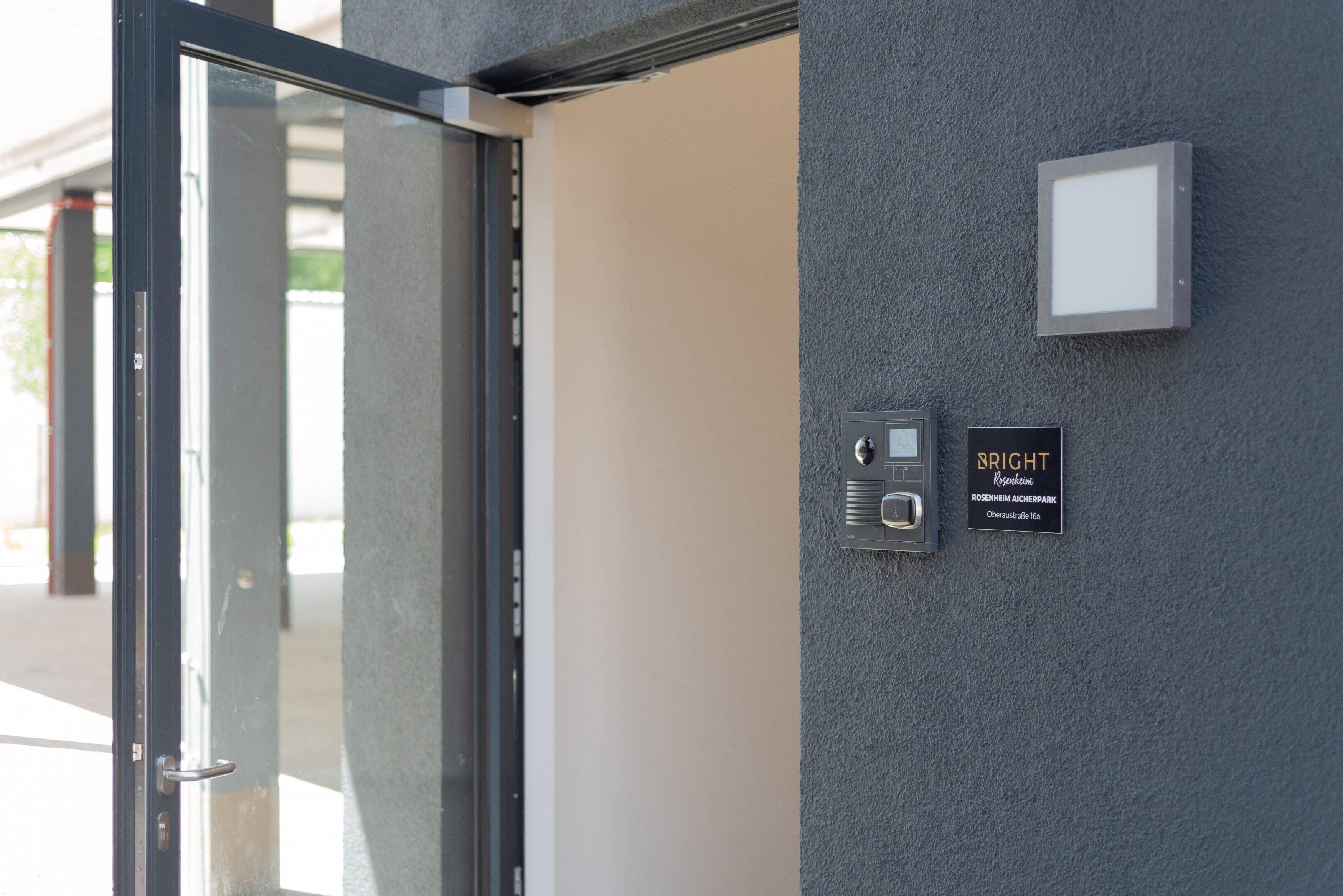 A door with a glass panel and a wall-mounted intercom system.