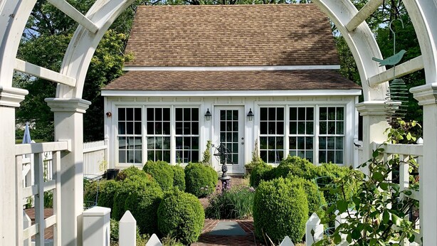 A white gazebo with a brick roof, surrounded by a white picket fence and lush greenery. - Historic Cottage on Ware River Estate (Gloucester)