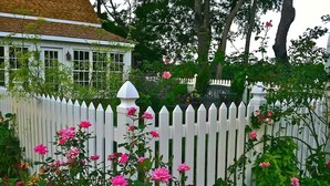 A white picket fence with pink flowers in the foreground. - Historic Cottage on Ware River Estate (Gloucester)