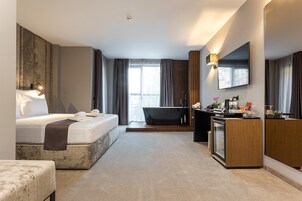 Una habitación de hotel moderna con una cama, un escritorio, una bañera y un espejo grande.