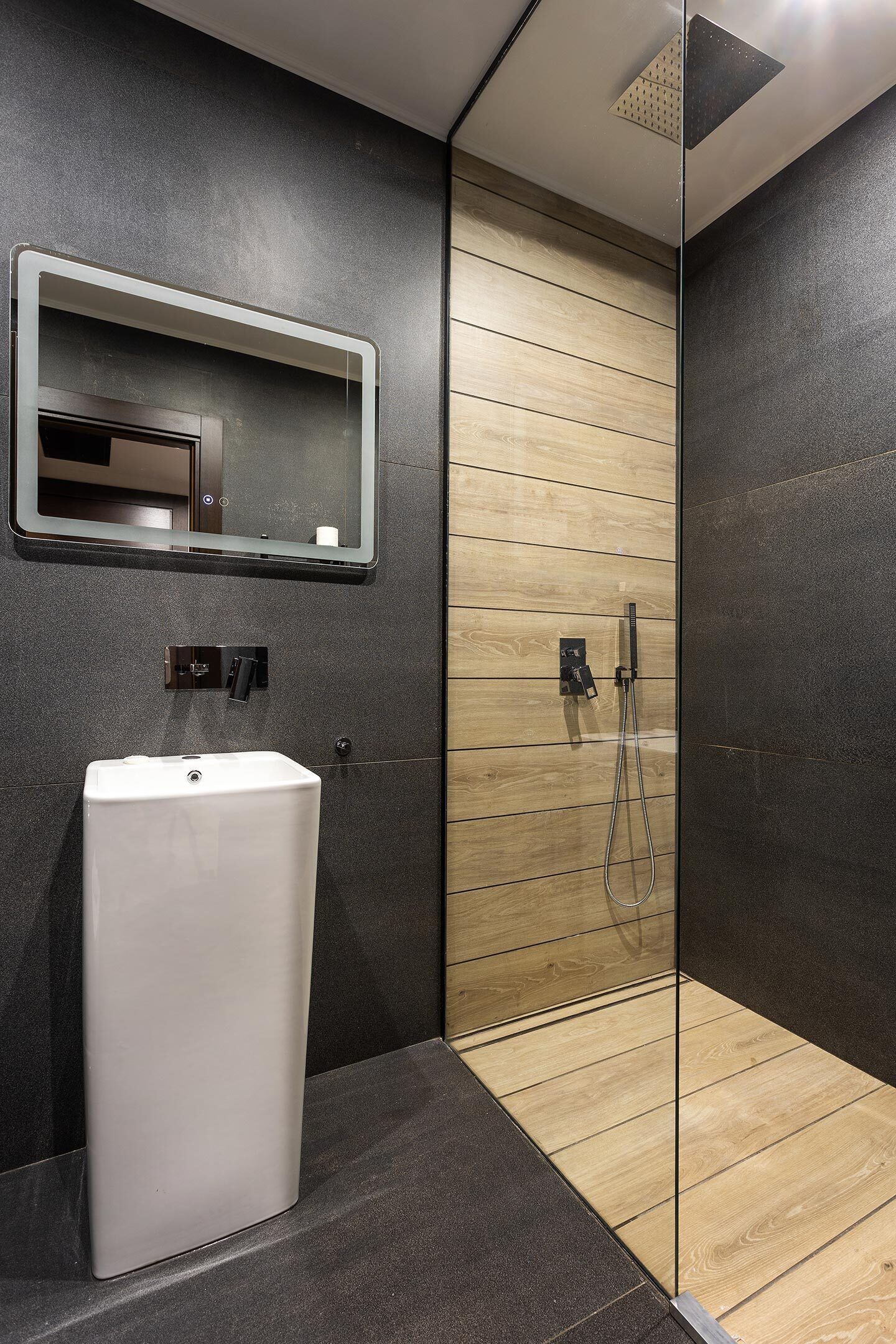 A modern bathroom with a white sink, a mirror, and a shower area.