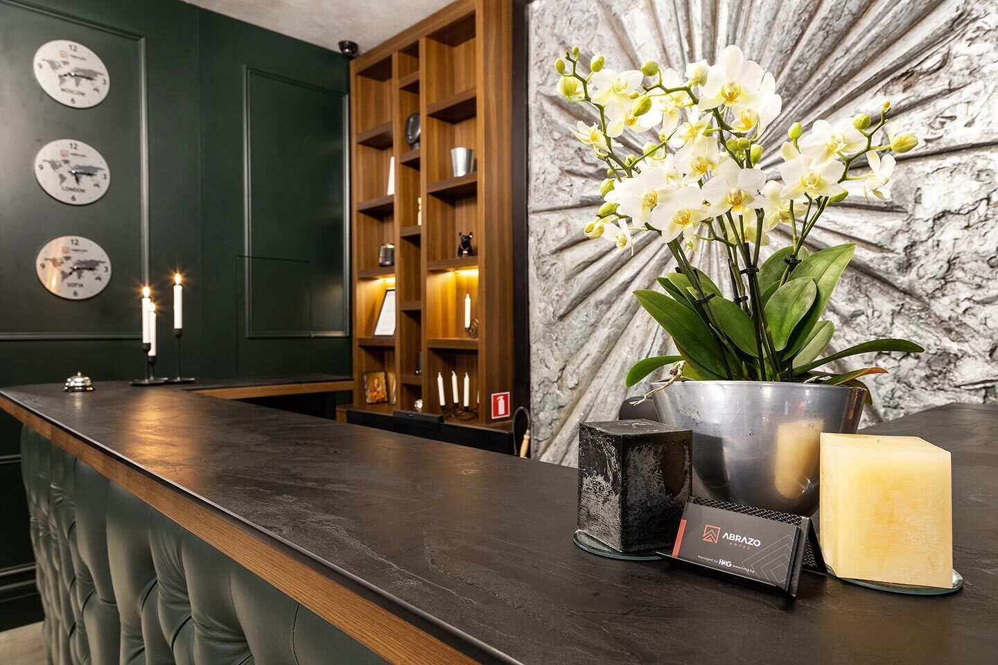 A reception area with a dark wood reception desk, a metal bucket with a plant, a candle, and a block of cheese.