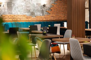 Un café moderno con pared de ladrillo, asientos azules y mesas de madera.