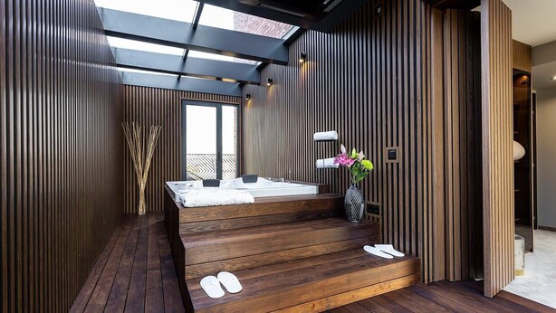 Een moderne badkamer met een houten bankje, een badkuip en een dakraam.