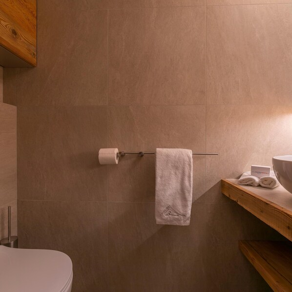 Une salle de bain avec une étagère en bois, une serviette et un porte-rouleau de papier toilette.