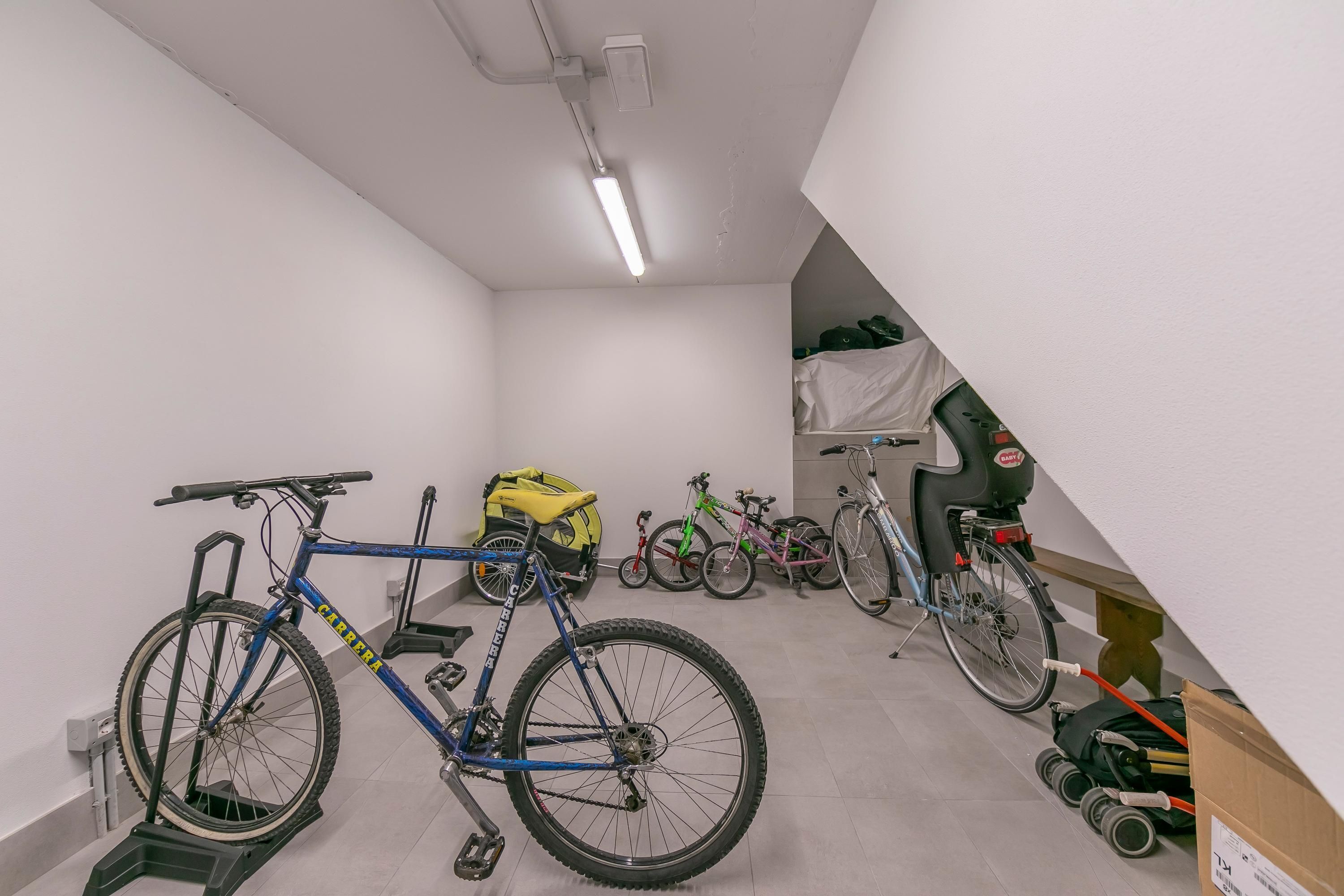 Ein Zimmer mit weißen Wänden, einer Deckenleuchte und Fahrrädern.