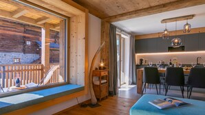 L’intérieur chaleureux d’un chalet avec un plancher en bois, un canapé bleu, un coin repas et une cuisine équipée d’appareils électroménagers modernes.