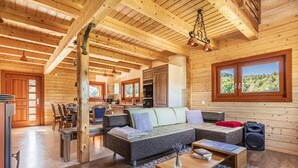 Een ruime woonkamer met een grote hoekbank, houten vloeren en een keuken op de achtergrond.