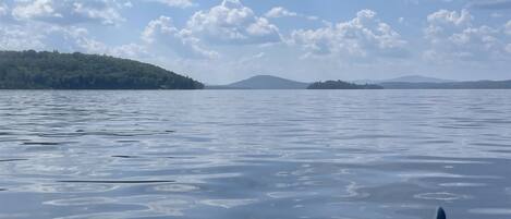 A calm lake with a paddle in the foreground, surrounded by a clear sky and distant hills.