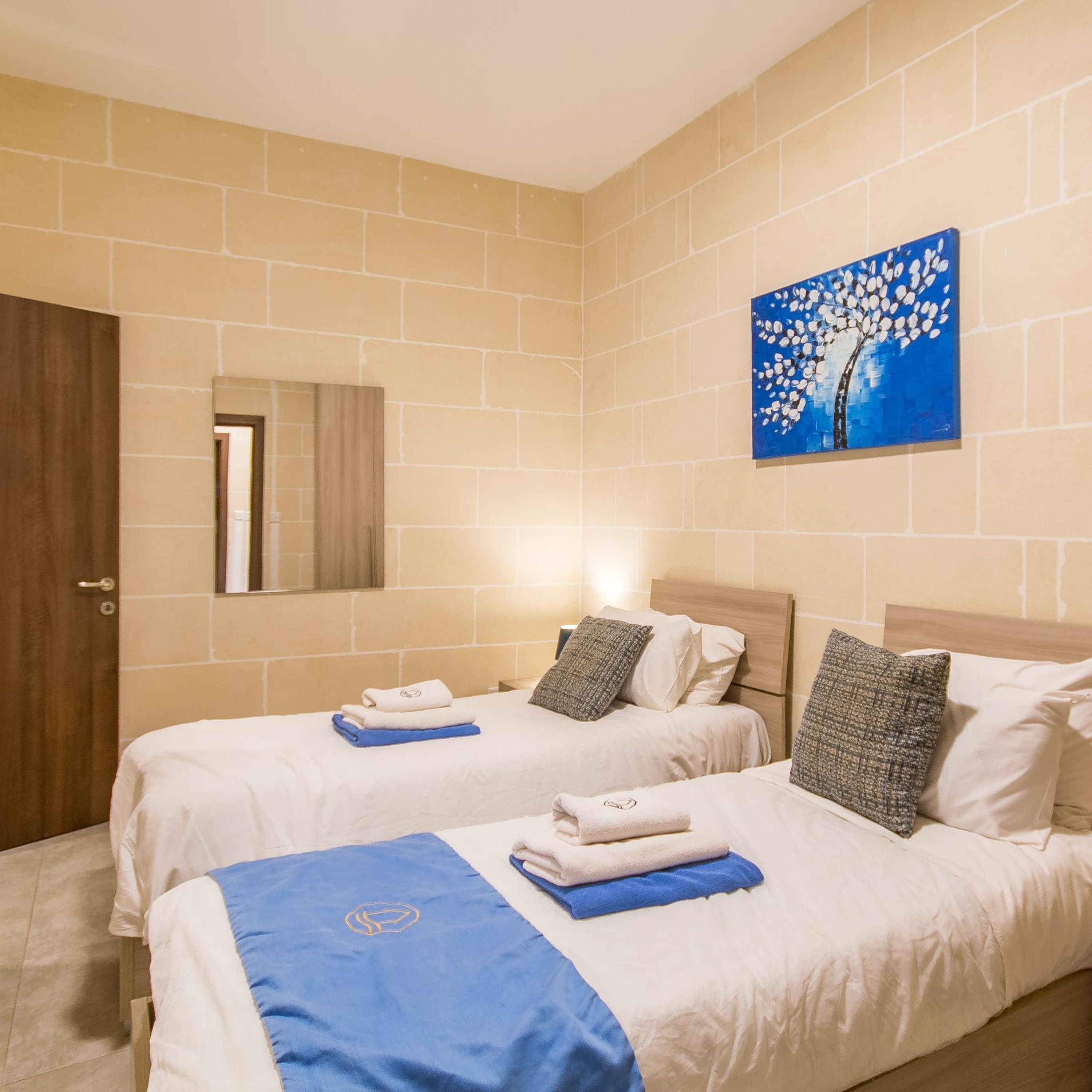 A hotel room with two beds, a large mirror, and a painting on the wall.