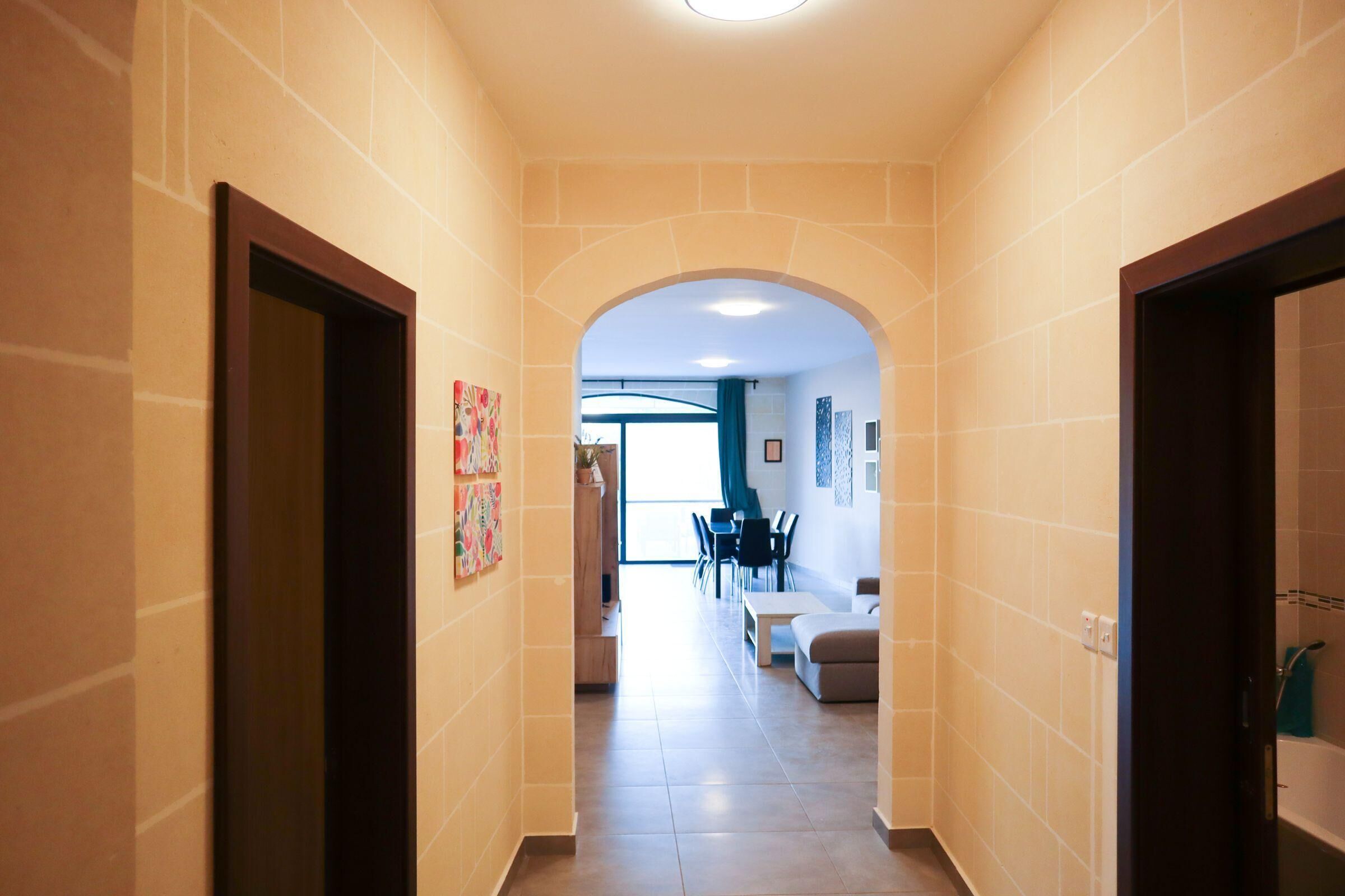 A narrow hallway with tiled walls and a ceiling light.
