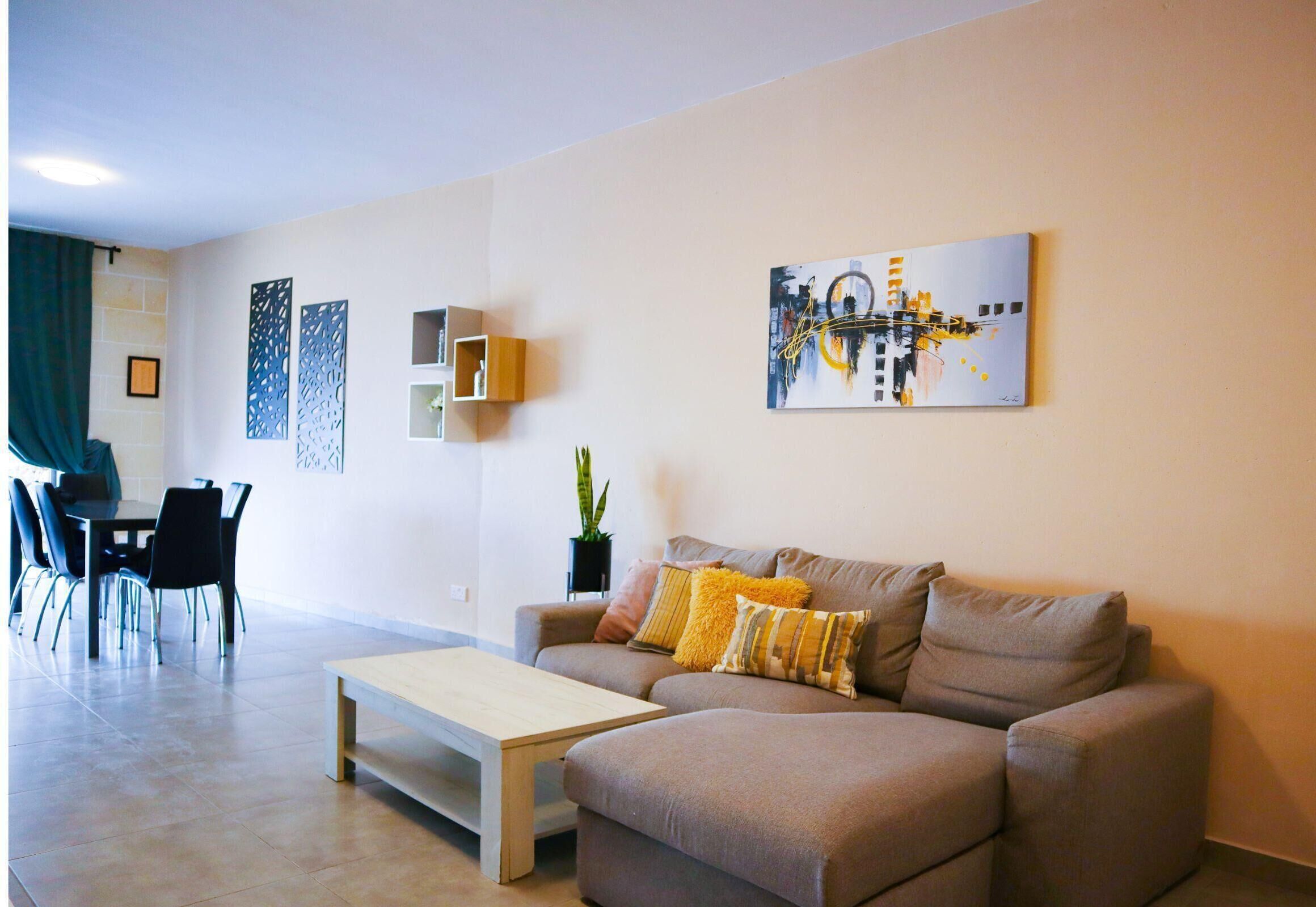 A modern living room with a sofa, a coffee table, and a dining area with chairs and a table.