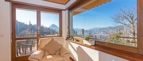 A room with a large window, a sofa, and a view of a cityscape.