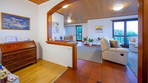 A spacious living area with a wooden ceiling, a wooden dresser, a sofa, and a view of the outdoors through large windows. - Chiara s Home in Pregassona Lugano (Lugano)